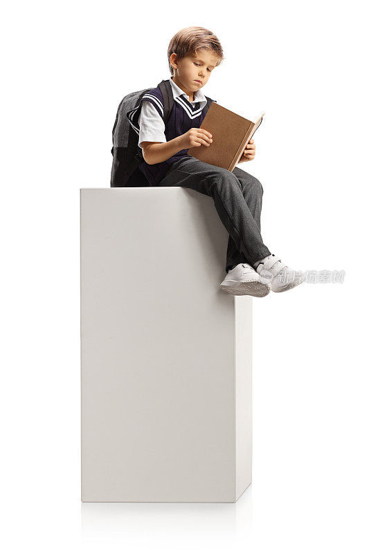 男生坐在一根高大的白色柱子上看书