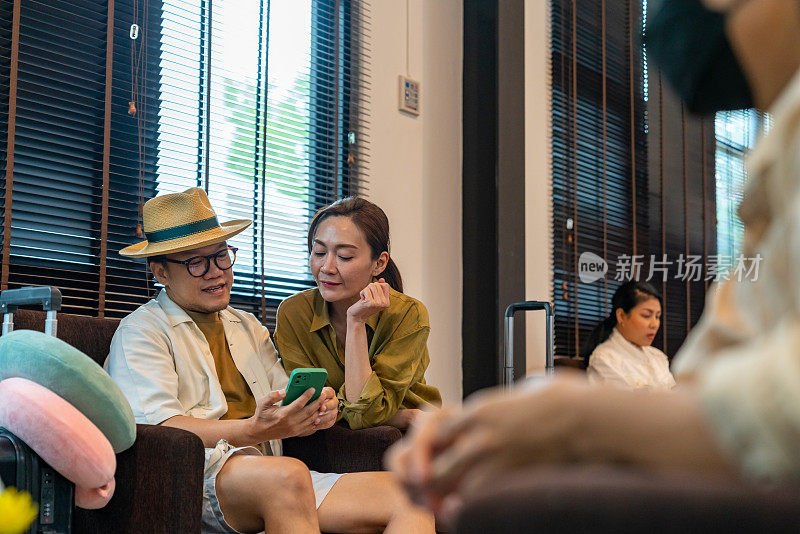 亚洲夫妇在机场候机楼的机场私人休息室使用手机。