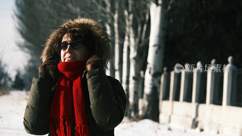 一名女游客在冬天的街道上被冻住了，她把脸藏在围巾里