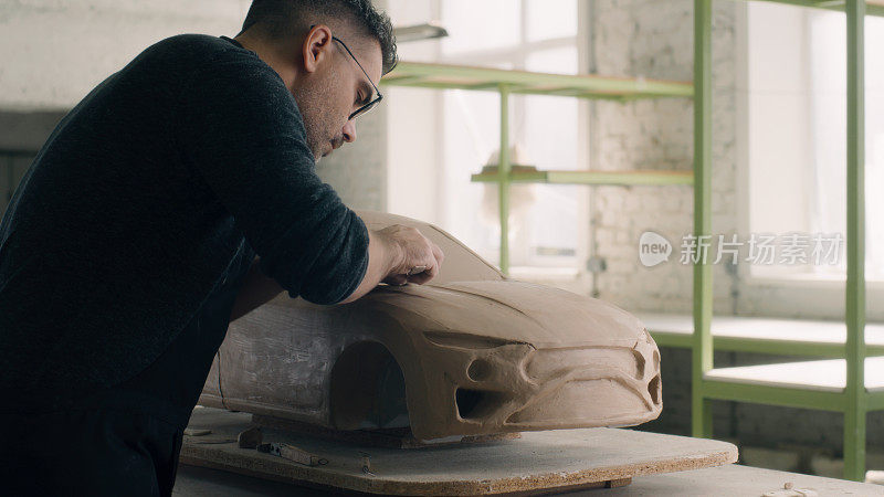 汽车设计师雕刻一个汽车模型使用有线工具雕刻出大块的粘土