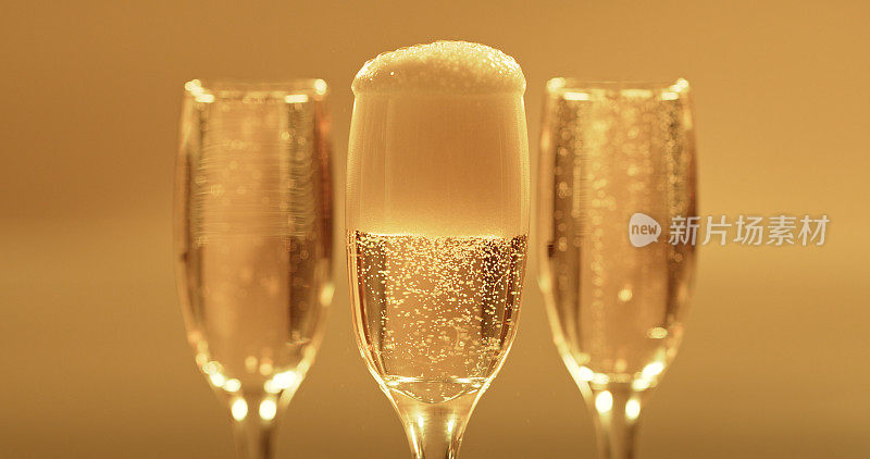香槟，玻璃或泡沫泡沫的黄金背景模型。豪华酒、金色起泡酒或啤酒在玻璃器皿或玻璃杯中起泡，用于活动庆典、聚会或餐饮。