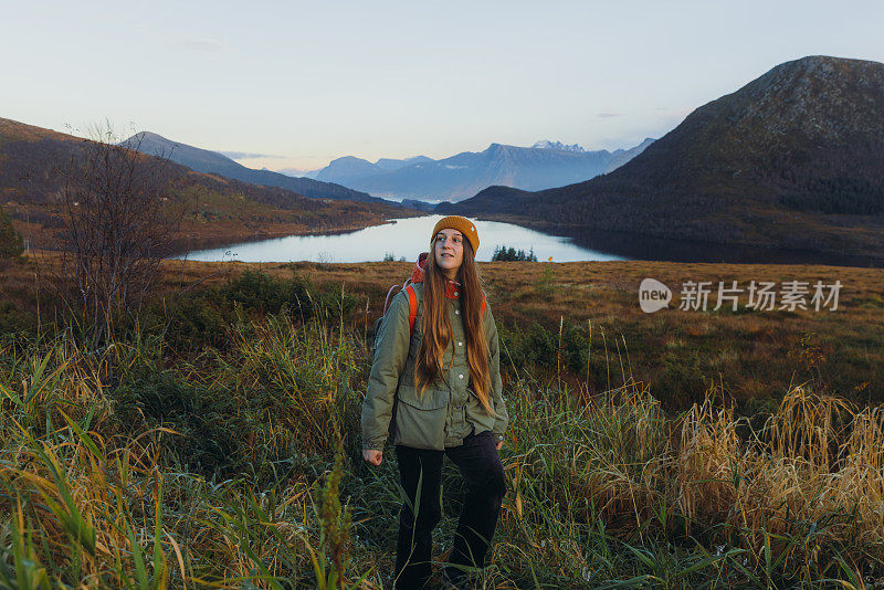 在挪威，一名女子在日落时分徒步到山上的湖边