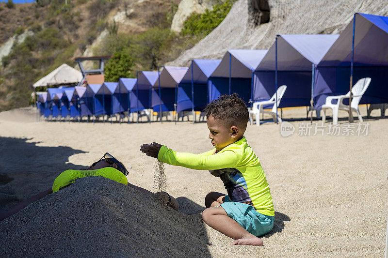 在海滩度假期间，母亲和儿子玩沙子，享受海里最好的时刻。