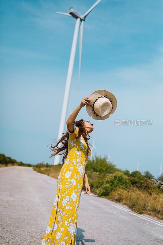 夏日里走过风力涡轮机的女人