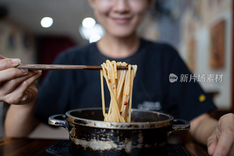 亚洲女士正在用筷子吃中国自制的辣面