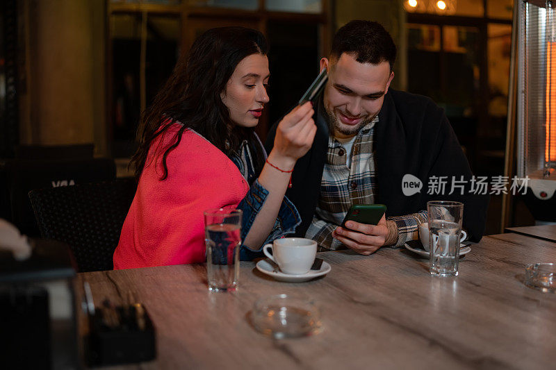 一对情侣在咖啡厅使用手机银行应用
