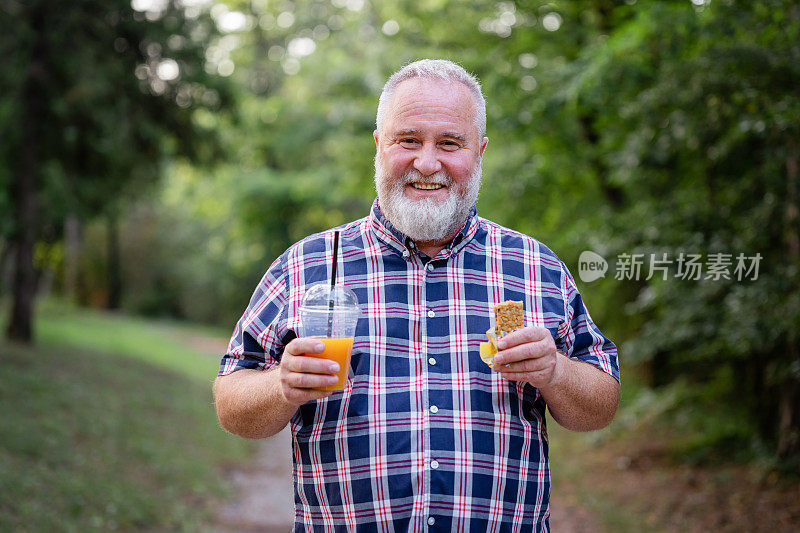 一个快乐的超重男人在公园里拿着奶昔和格兰诺拉麦片棒