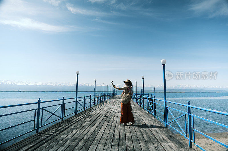 开朗的成熟女游客正在拍摄她的湖滨之旅