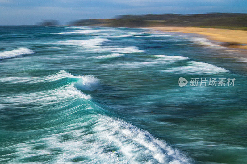 长时间曝光平滑的海浪翻滚到岩石海滩