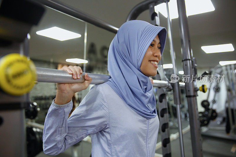 印度尼西亚穆斯林妇女用杠铃做深蹲训练