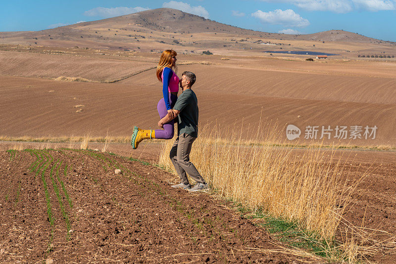 健康的生活方式:家庭野餐和锻炼。丈夫和妻子在耕地上玩耍。