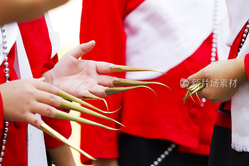 在清迈省，穿着红色衣服的十几岁的泰国朗姆酒舞者的一双金色指甲延伸的手