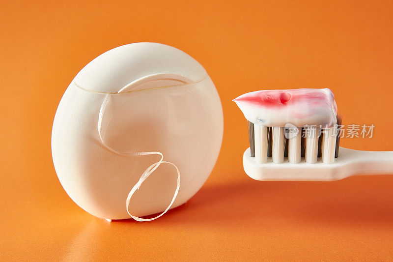 牙刷，牙膏和牙线在橙色的背景。牙科保健。口腔卫生。