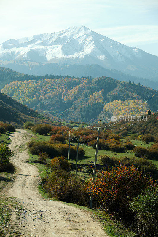 在阳光明媚的秋日里，蜿蜒的土路穿过山峡