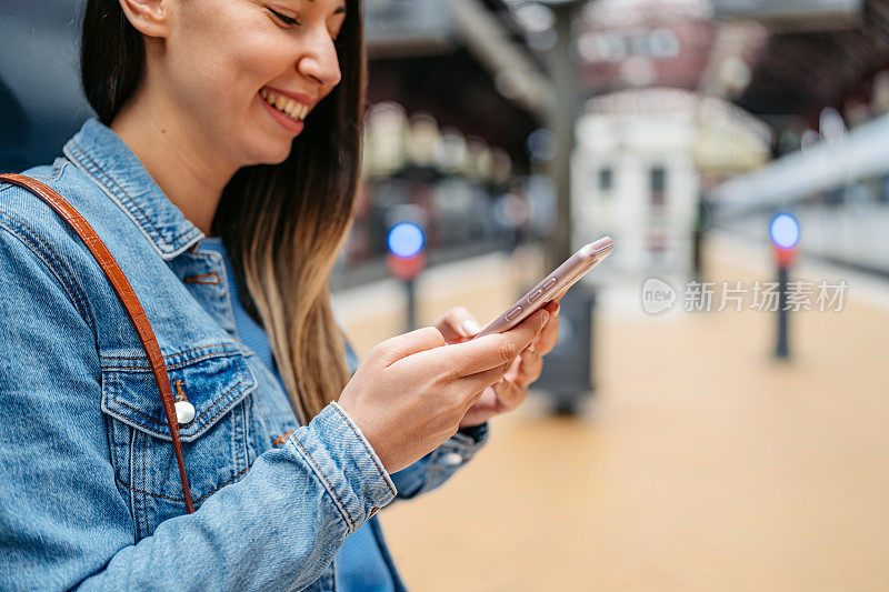 在丹麦哥本哈根火车站，一名年轻女子在等火车的时候玩手机