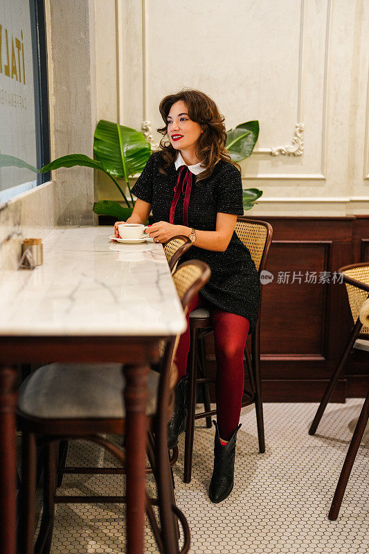 年轻漂亮的女人在咖啡馆用咖啡杯喝咖啡