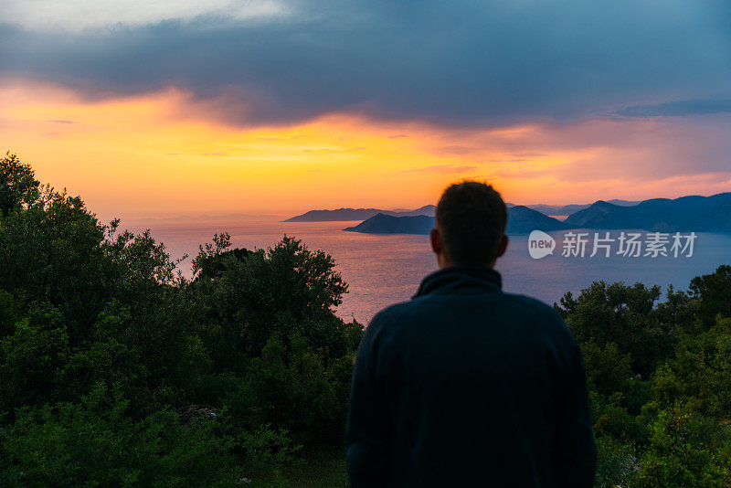 男子欣赏神奇的日落，俯瞰五彩缤纷的大海