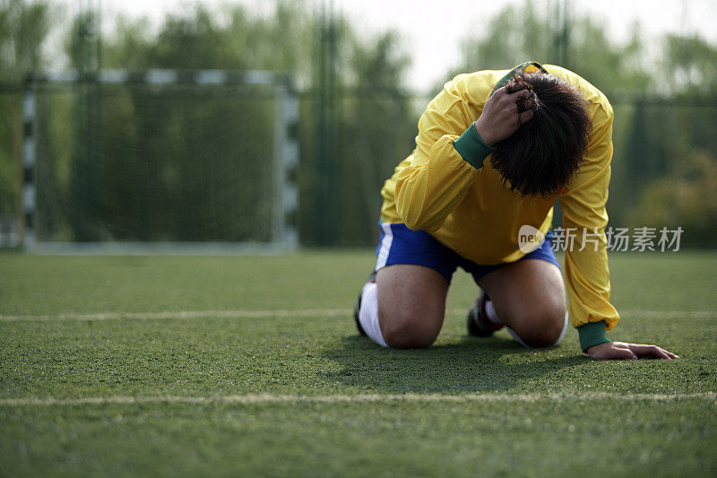 足球运动员趴在草地上
