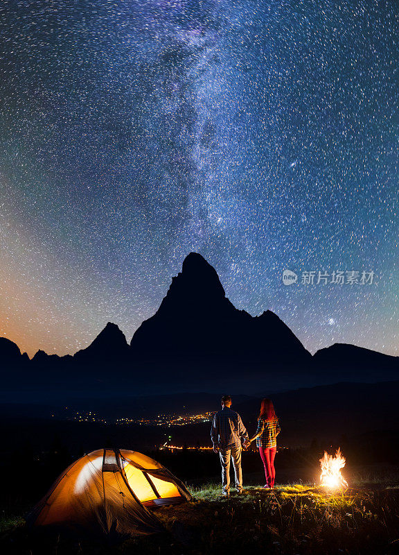 一对游客情侣站在火旁欣赏星空