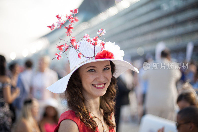 美丽的女孩戴着樱花帽在赛马