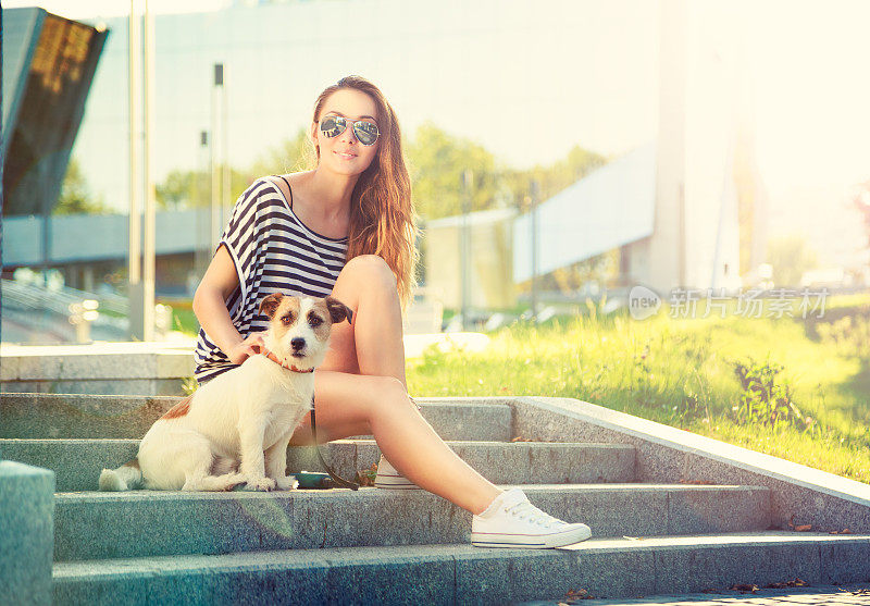 快乐的嬉皮士女孩和她的狗在城市