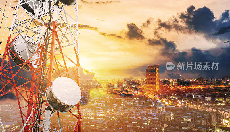 双曝光电信塔与电视天线和卫星天线在日落，与城市背景