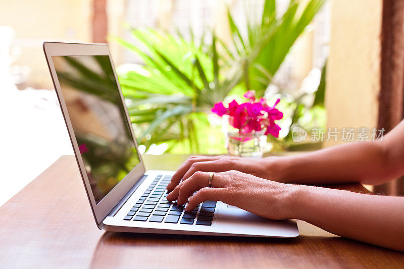 一个在热带度假的女人在酒店用笔记本电脑