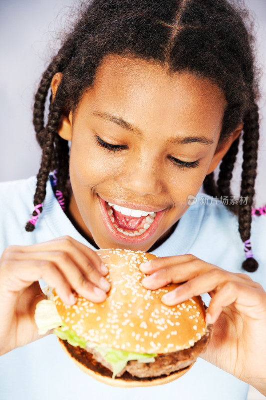 小女孩吃着汉堡，享受着快餐。