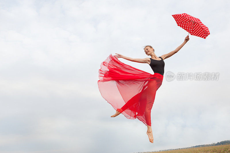 带着伞在天空中飞翔的年轻女子