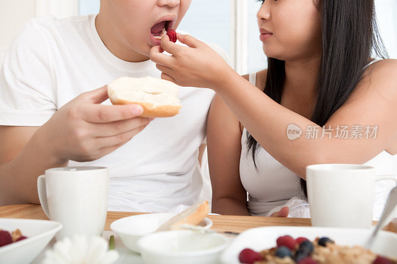 一对亚洲年轻夫妇在床上吃早餐