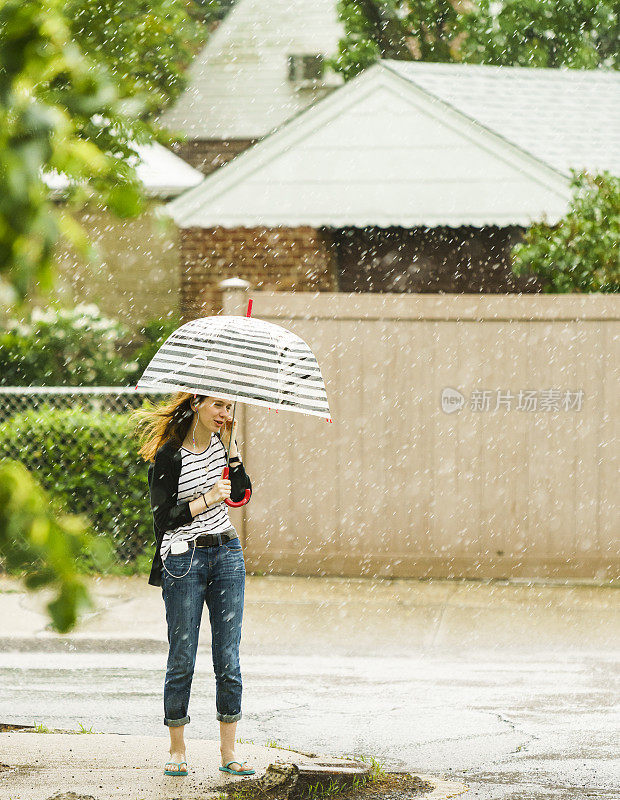 少女撑着伞在雨中走在街上。纽约皇后区