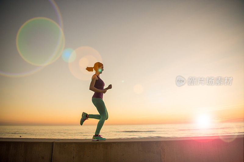 年轻女子在夕阳下奔跑的剪影