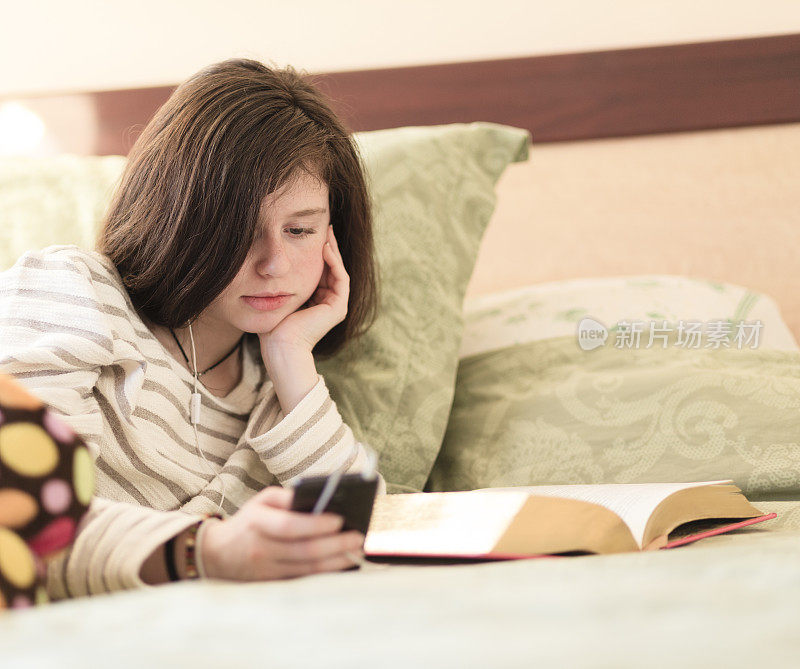 十几岁的女孩穿着睡衣在床上看书