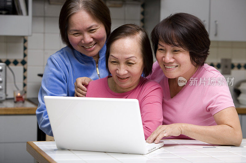 亚洲年长成年女性在厨房使用笔记本电脑，拷贝空间