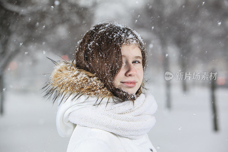 雪下穿着白色夹克的漂亮少女