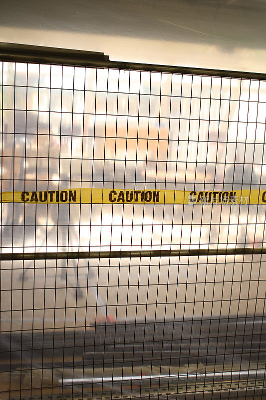 黄色“警告”胶带穿过金属栅栏，区域正在施工中