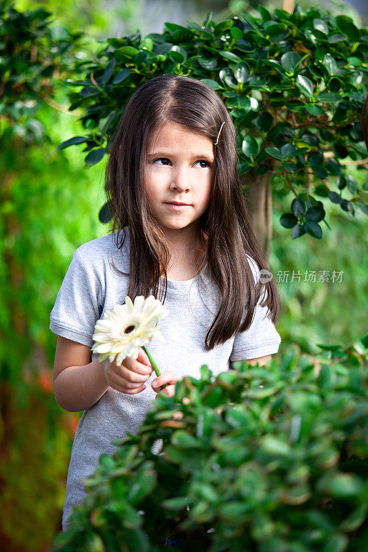 可爱的小女孩在花园里捧着花