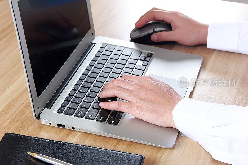 女性用手在笔记本电脑上打字