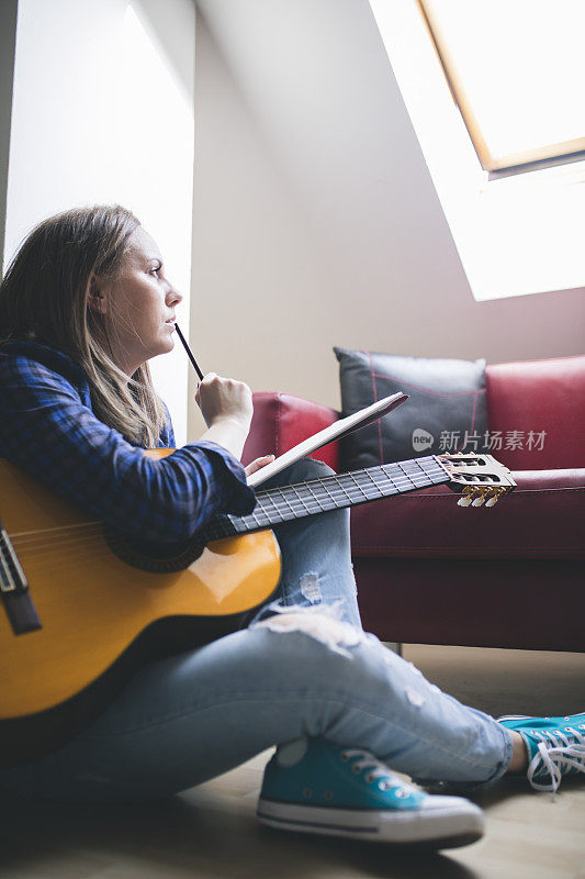 作曲家有乐趣享受爱好概念和写在笔记纸上的原声吉他附近。学习乐器。