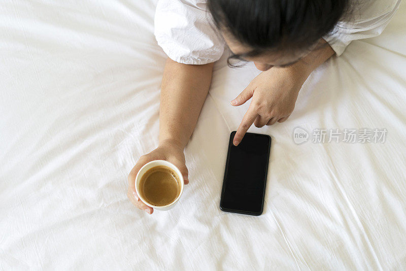 女孩在床上看手机喝咖啡