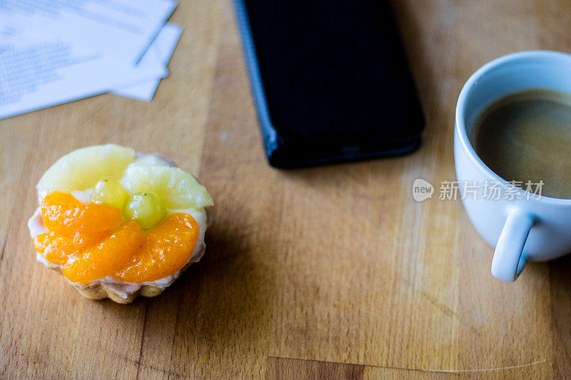 美味的松饼和水果放在木制餐桌上。咖啡和电话留言。的气氛。