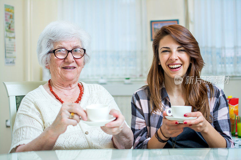 一个奶奶和她的孙女在家里喝咖啡聊天的肖像。