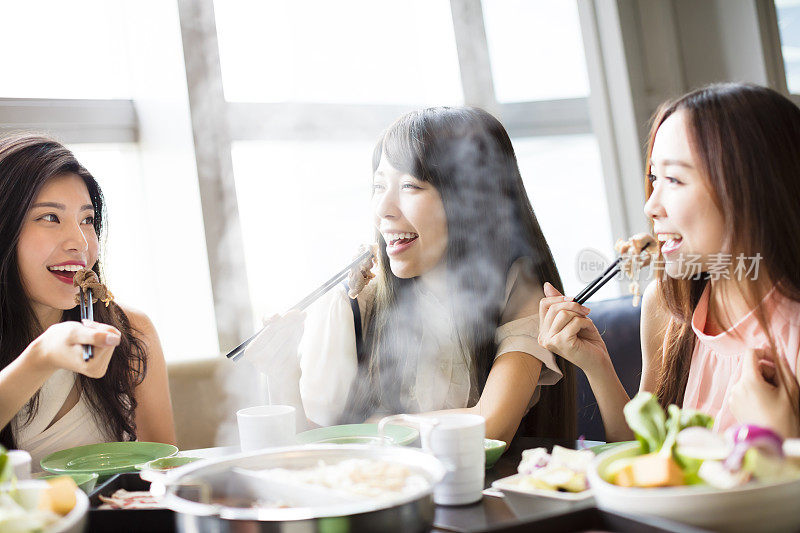 快乐的年轻女性团体吃火锅