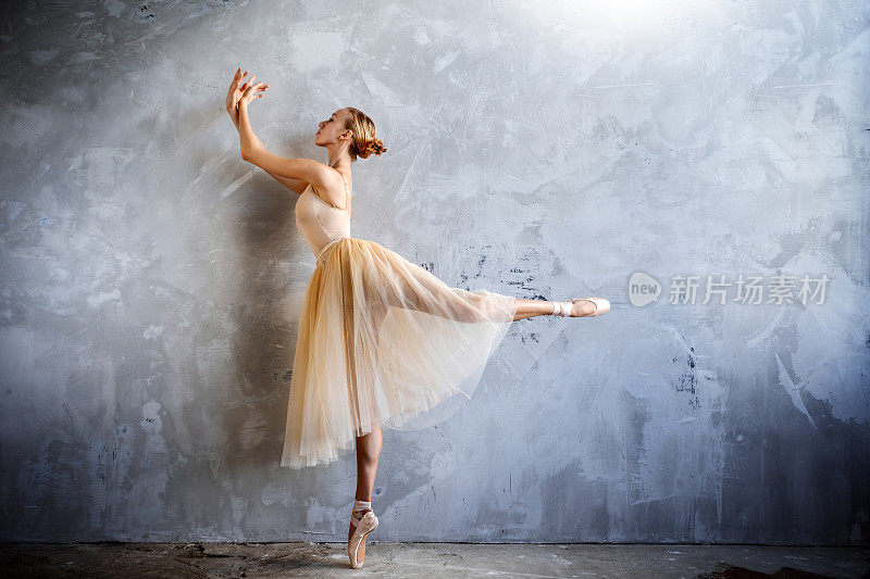 年轻的芭蕾舞演员穿着金色的舞蹈服装在阁楼工作室摆姿势