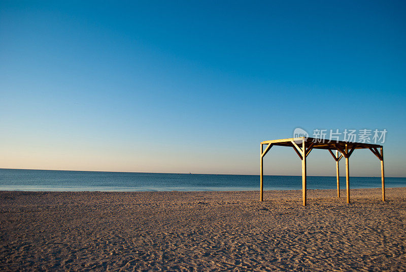 早晨海边沙滩上的木制天篷凉亭