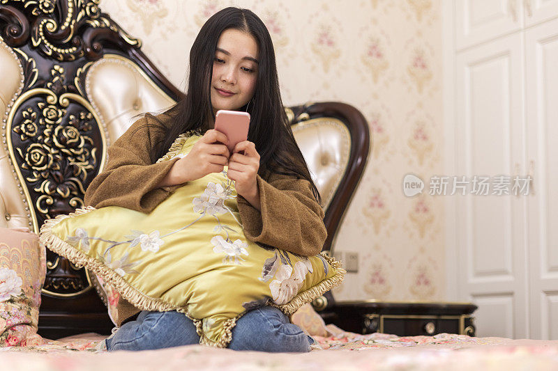 年轻女子躺在床上玩智能手机