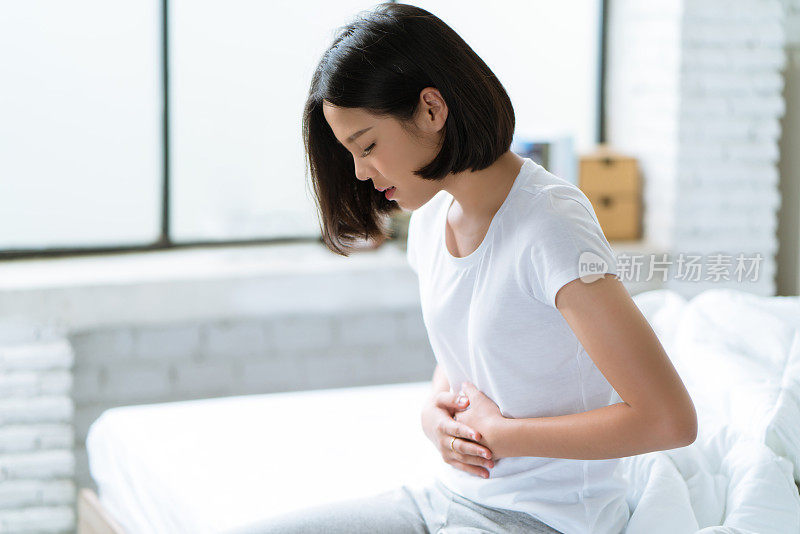 亚洲女人，她的胃疼得厉害她在半夜睡觉的时候醒来。