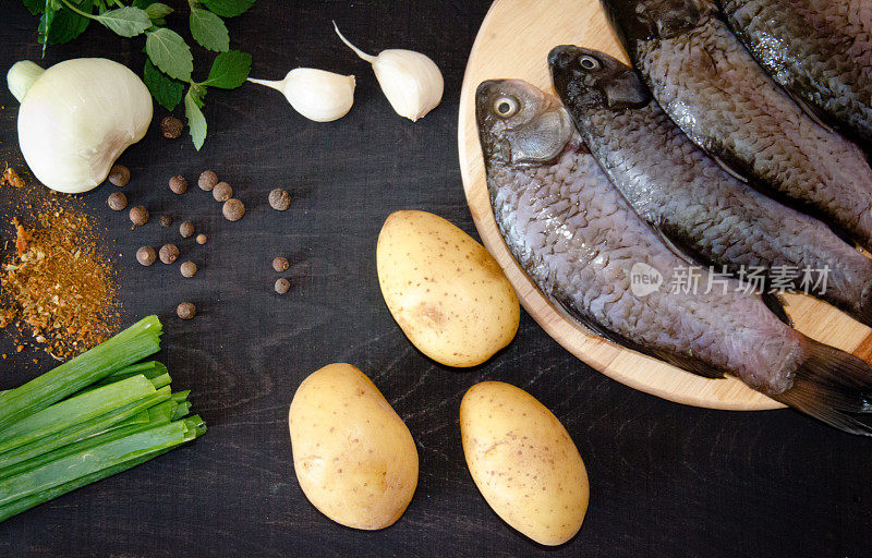 新鲜的鱼，蔬菜和土豆香料在黑色的背景
