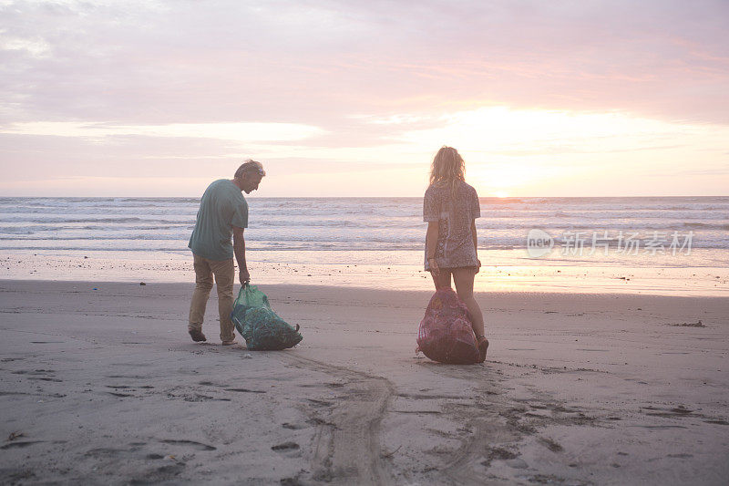 日落时分，男男女女清扫海滩上的垃圾