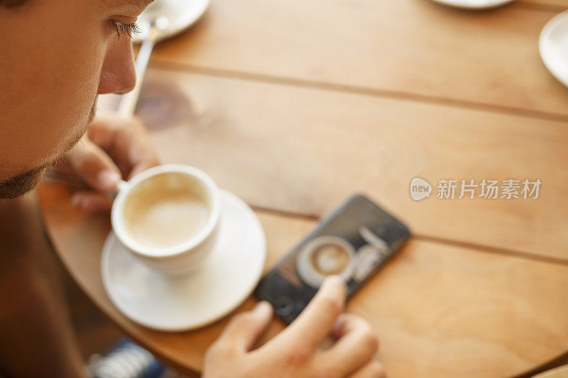 学生使用触摸屏智能手机，一边喝咖啡一边上网。